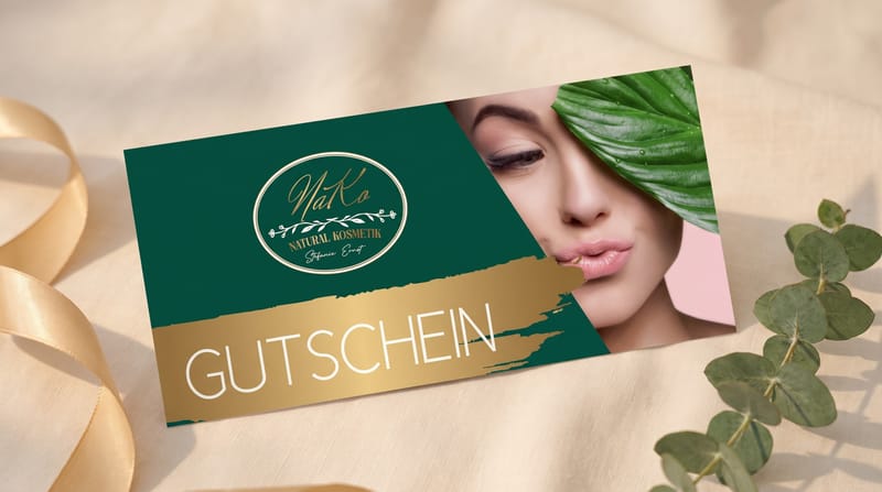 NAKO-Gutschein, elegant auf cremefarbenem Leinen mit Goldband und Eukalyptus arrangiert